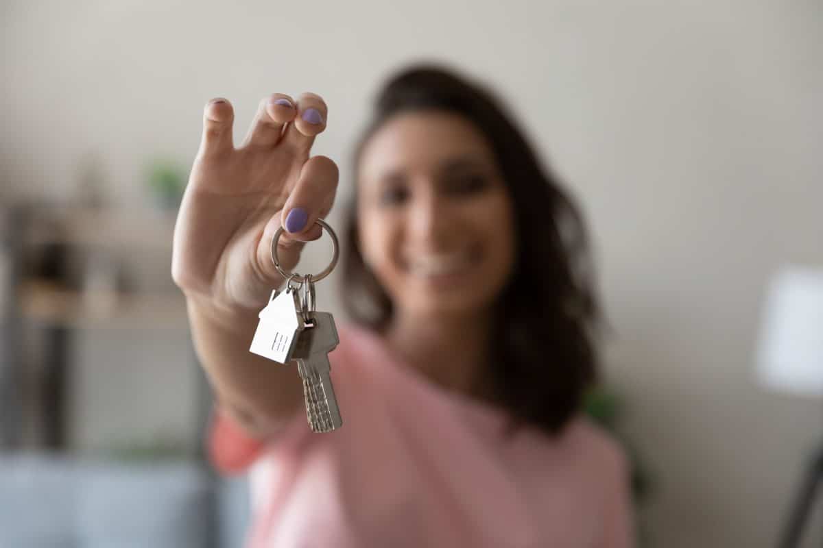 Vrouw houdt sleutel van eerste woning voor zich uit.